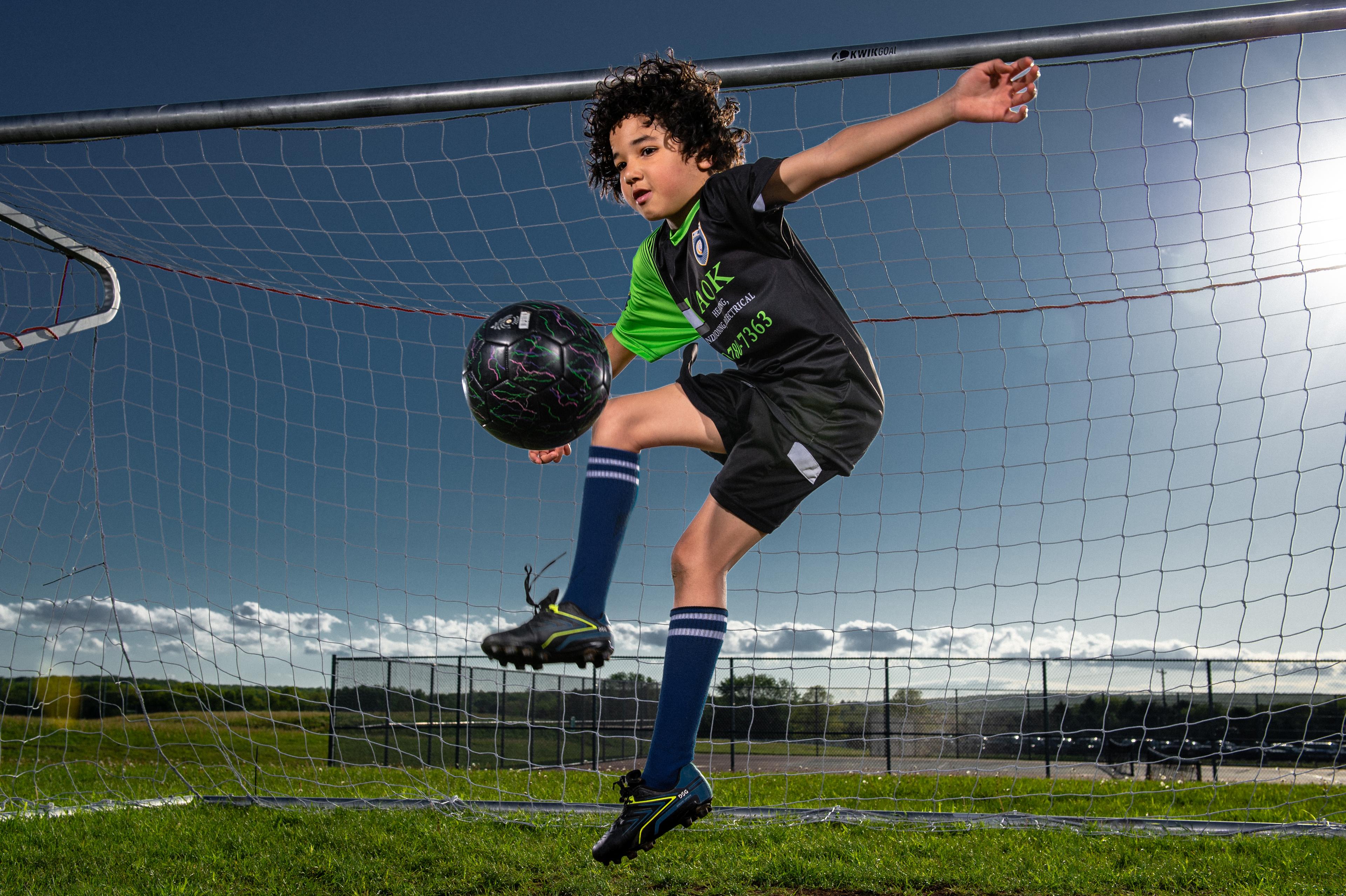 soccer player action shot, jumping and kicking the ball.